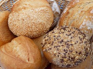 Photograph of a variety of loaves of bread in a wicker basket.